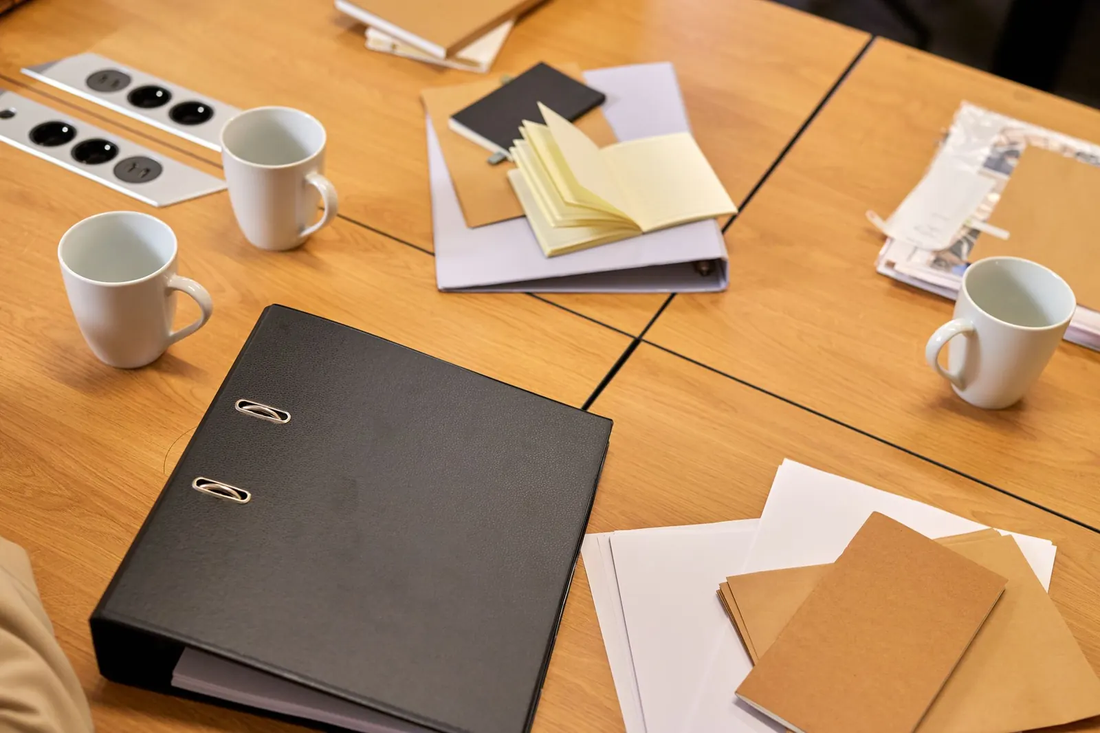 Black ring binder and papers on a wooden table